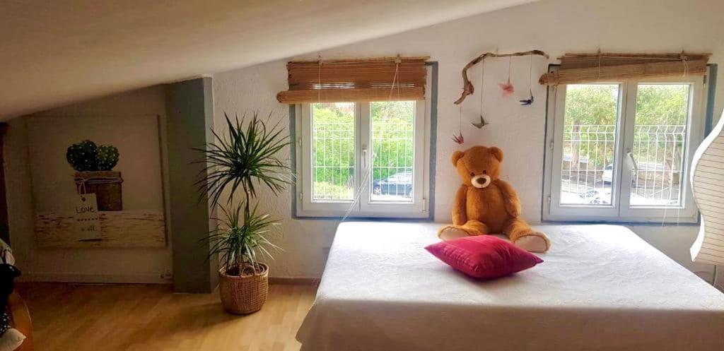 un osito de peluche sentado en una cama en un dormitorio en Maison du bonheur, en Borgo