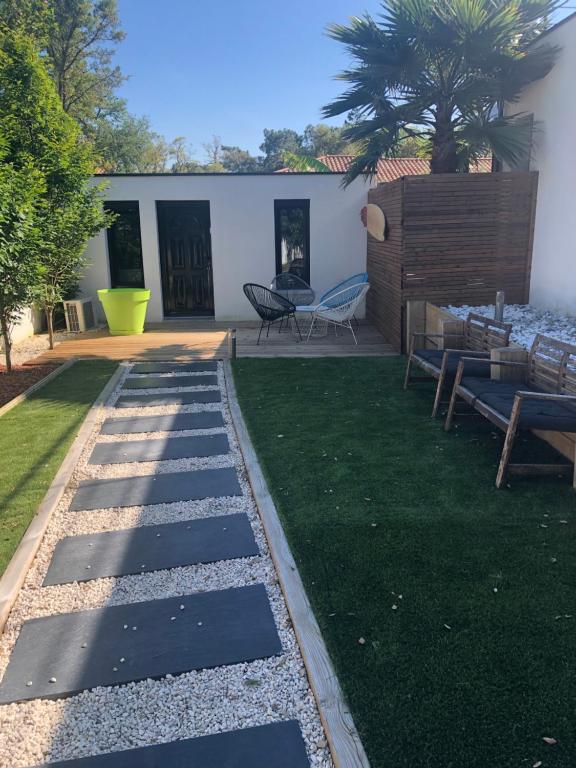 a garden with a patio with a table and chairs at Maison bord mer in Labenne