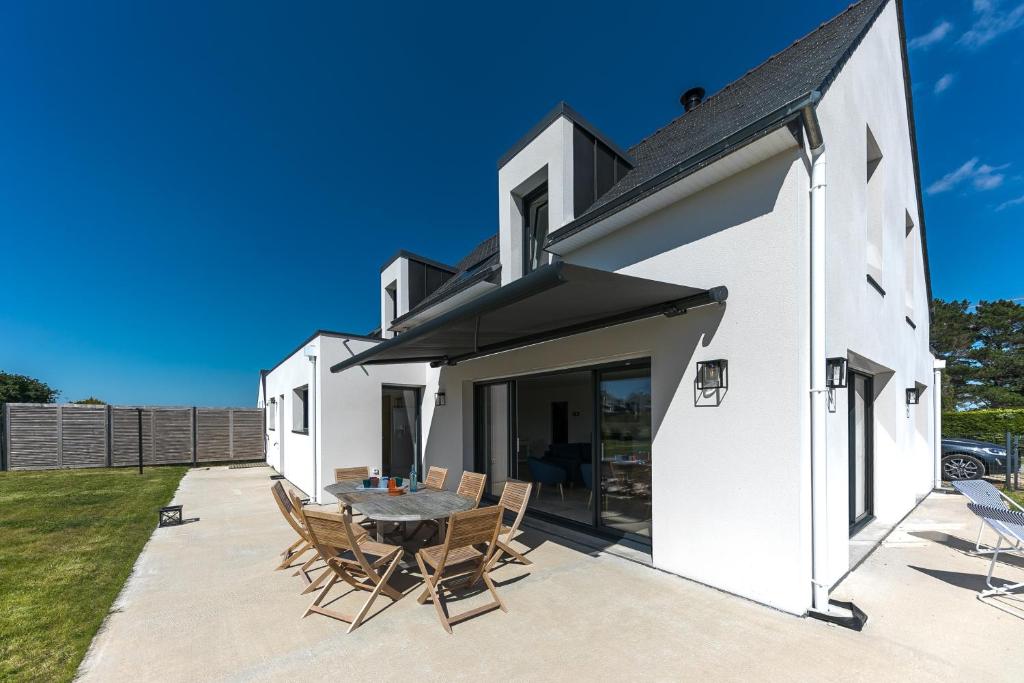 een wit huis met een patio met een tafel en stoelen bij TI LAOUEN - 300 m de la plage in Sarzeau