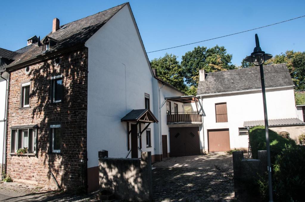 an old white building with a black door and a street light at Ferienhaus an der Mosel in Senhals