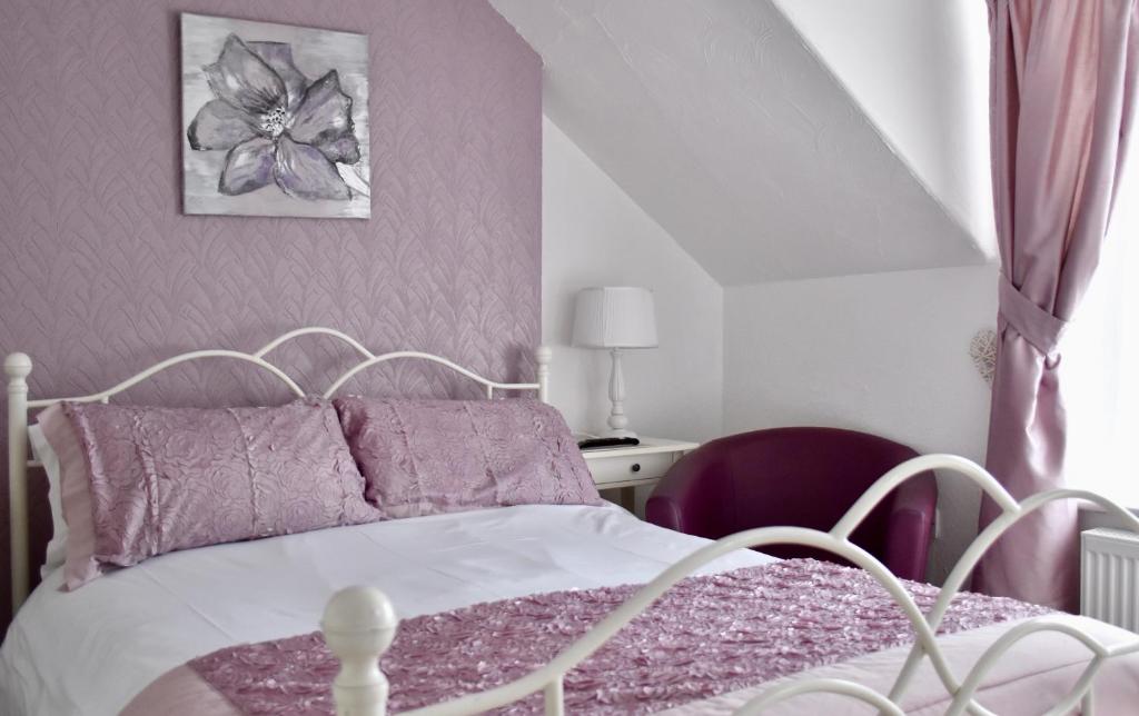 a bedroom with a white bed with purple pillows at Witchingham B&B in Holyhead