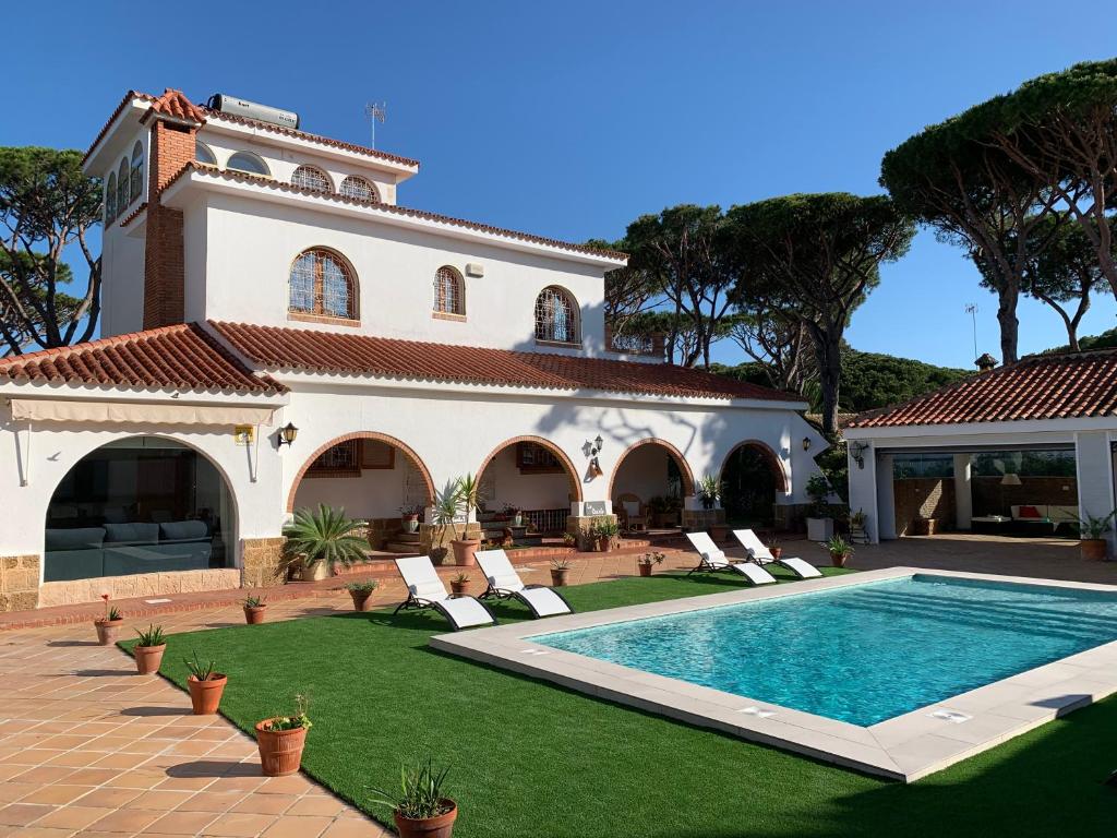 a villa with a swimming pool and a house at La Quinta - La Barrosa in Chiclana de la Frontera