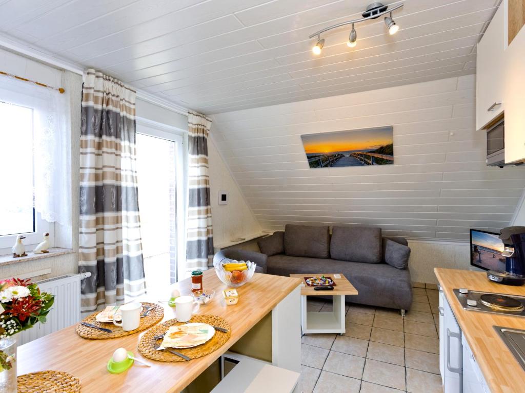 eine Küche und ein Wohnzimmer mit einem Sofa und einem Tisch in der Unterkunft FeWo Sonnenanbeter in Dorum