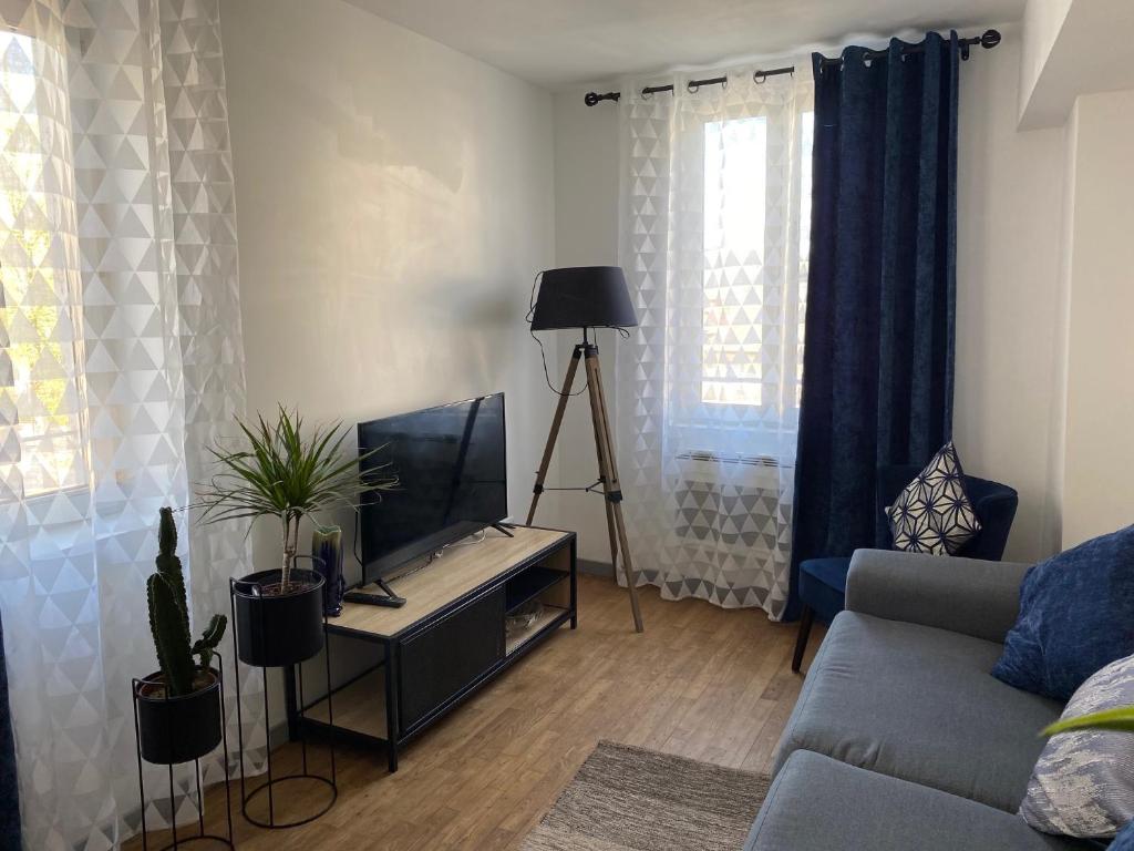 een woonkamer met een bank en een flatscreen-tv bij Aventurine in Terrasson