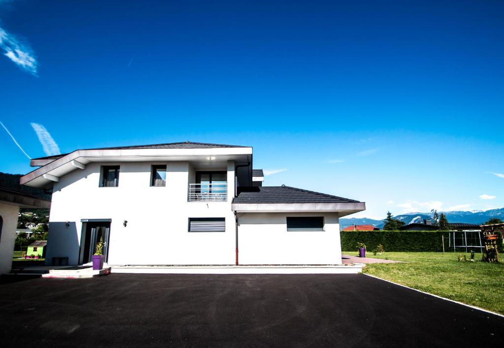 a white house with a driveway in front of it at Nuitée en appartement in Marignier