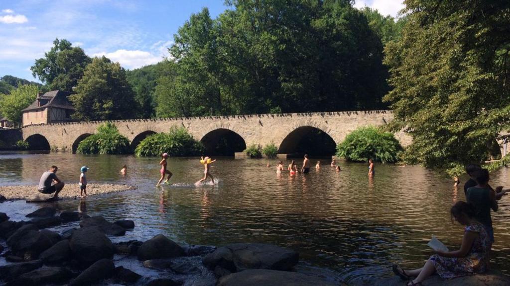 een groep mensen die in het water spelen bij een brug bij La mémée du Saillant in Voutezac