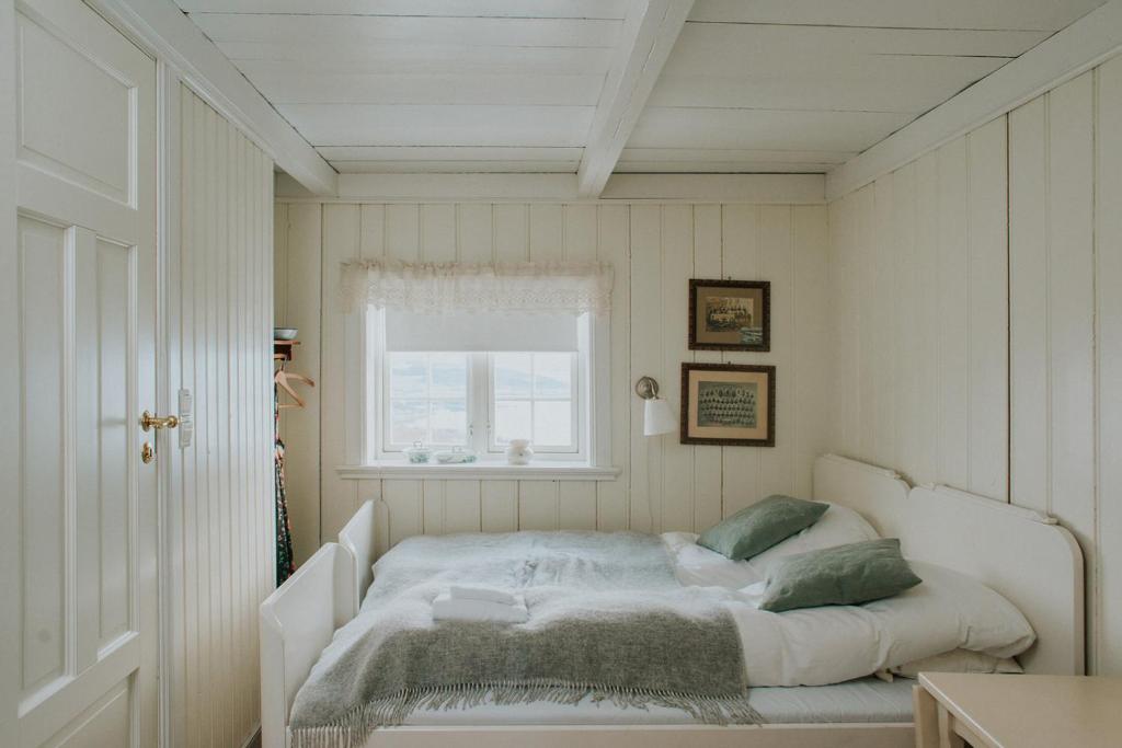 a white bed in a room with a window at Husfrua Gårdshotell in Straumen