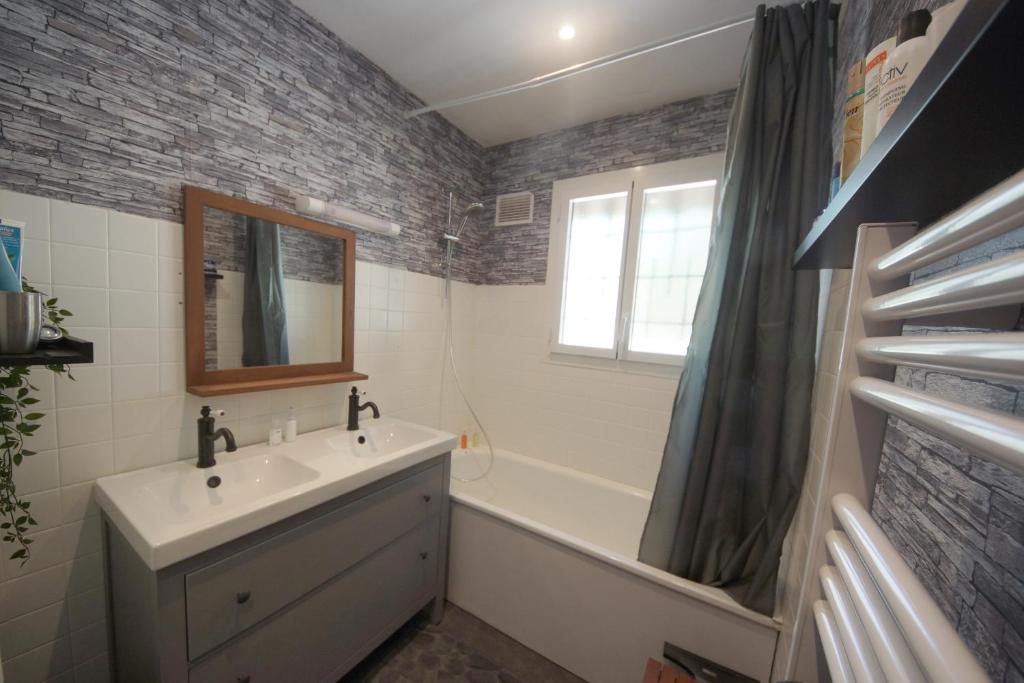 a bathroom with a sink and a tub and a mirror at Chez Flo et Marc in Chouzy-sur-Cisse