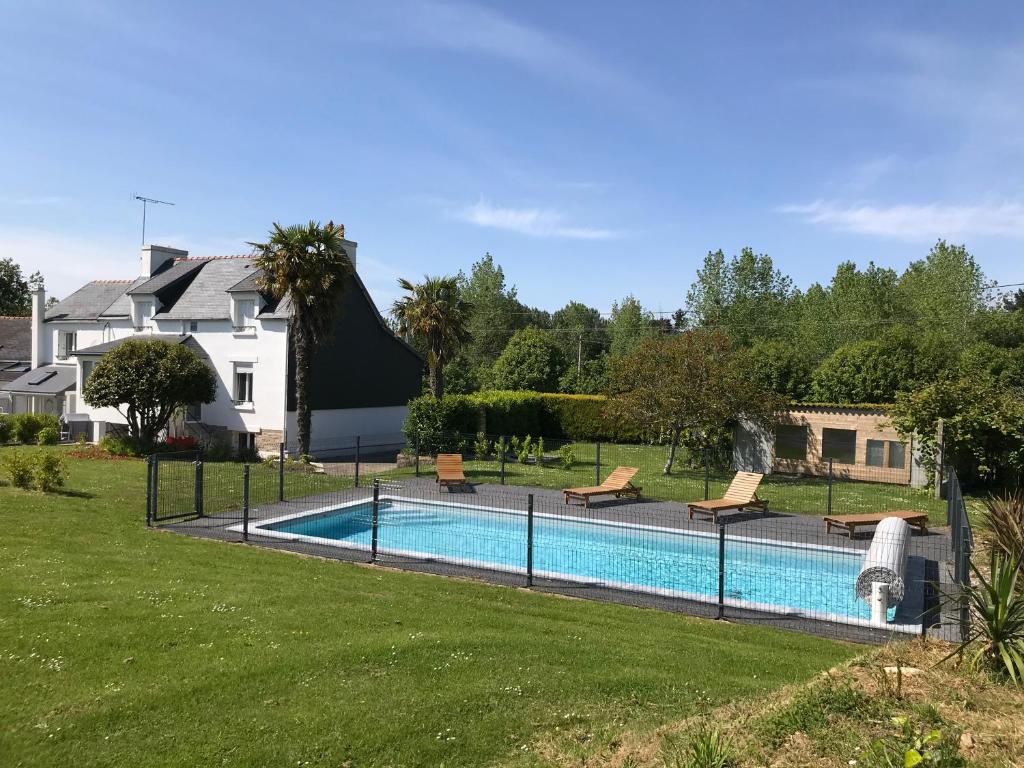 a swimming pool in a yard next to a house at Maisons Les Gites de l'Odet in Clohars-Fouesnant