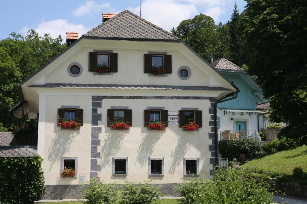 une maison blanche avec des fleurs dans les fenêtres dans l'établissement Apartments Cvetje v Jeseni, à Škofja Loka