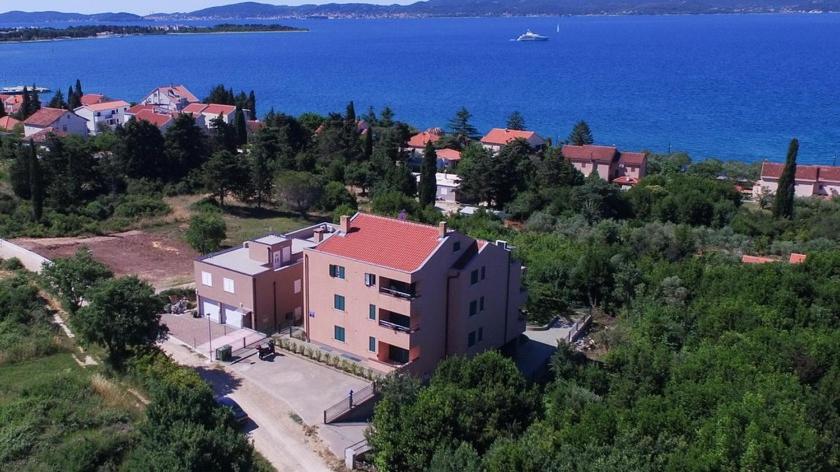 an aerial view of a house on a hill next to the water at Apartments Ivan in Zadar