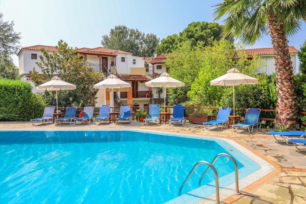 a swimming pool with chairs and umbrellas at Sergios in Koukounaries