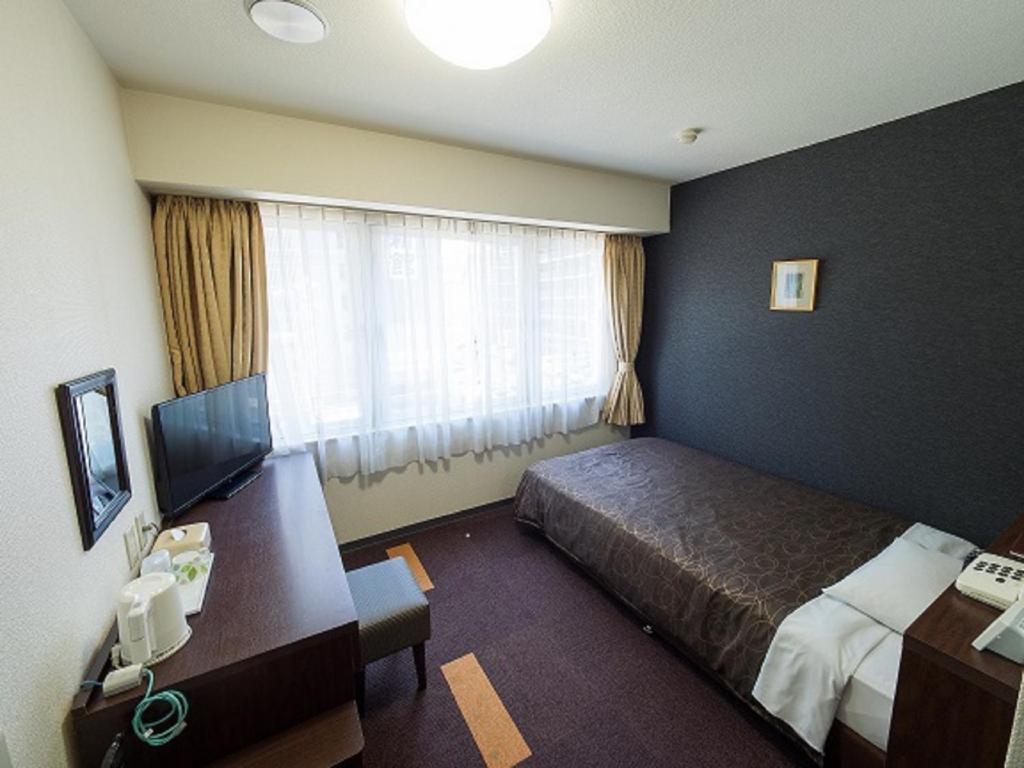 Pokój hotelowy z łóżkiem, biurkiem i telewizorem w obiekcie Hotel Shin Osaka / Vacation STAY 81494 w Osace