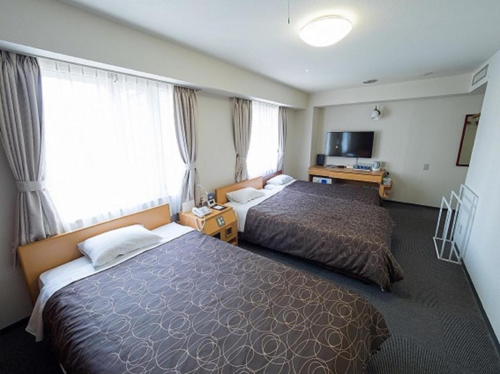大阪市にあるHotel Shin Osaka / Vacation STAY 81543のベッド2台とテレビが備わるホテルルームです。