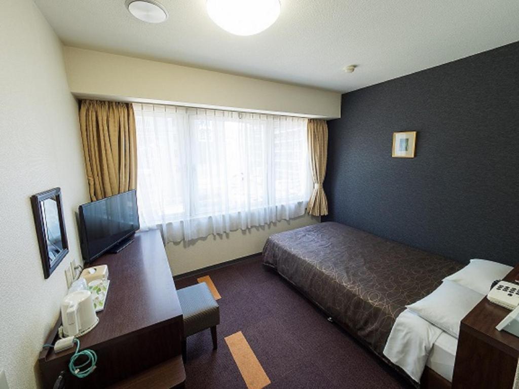 Habitación de hotel con cama, escritorio y ventana en Hotel Shin Osaka / Vacation STAY 81522 en Osaka