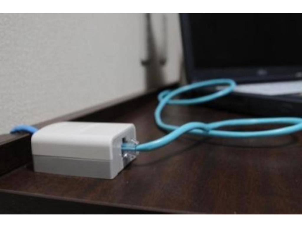 a white device with a blue cord sitting on a desk at Hotel Shin Osaka / Vacation STAY 81492 in Osaka