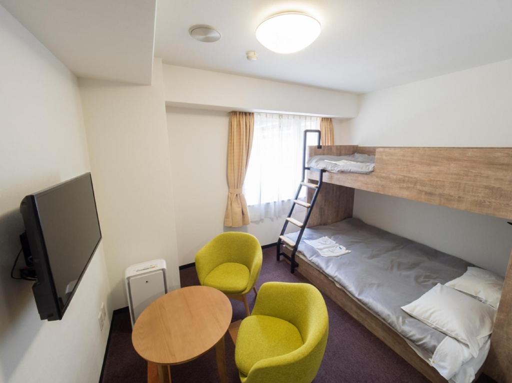 a small room with a bunk bed and a table and chairs at Hotel Shin Osaka / Vacation STAY 81532 in Osaka