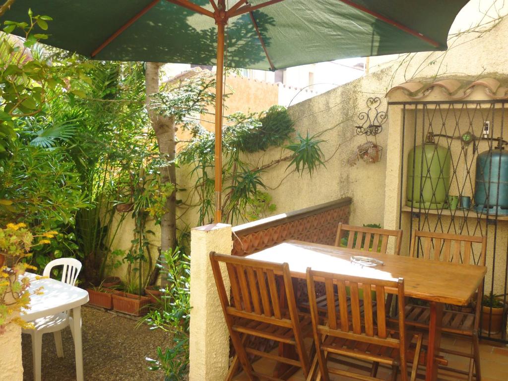 - une table et des chaises sous un parasol sur la terrasse dans l'établissement Maison charmante à Sainte-Marie avec grand jardin, à Sainte-Marie-la-Mer