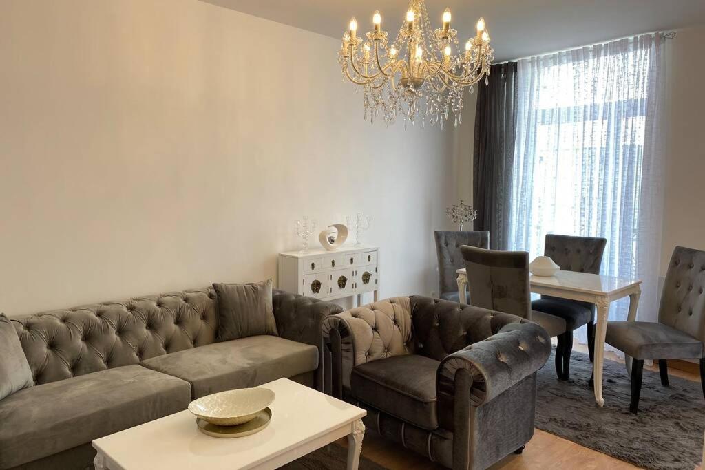 a living room with a couch and chairs and a chandelier at Sélénite in Terrasson-Lavilledieu