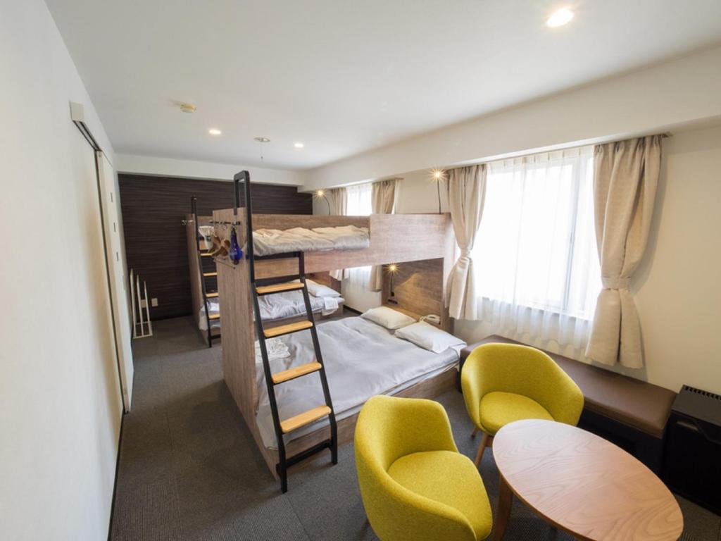 Cette chambre comprend 2 lits superposés, une table et des chaises. dans l'établissement Hotel Shin Osaka / Vacation STAY 81530, à Osaka