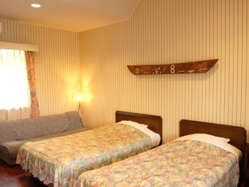 a hotel room with two beds and a couch at Amami Resort Bashayamamura / Vacation STAY 81477 in Amami