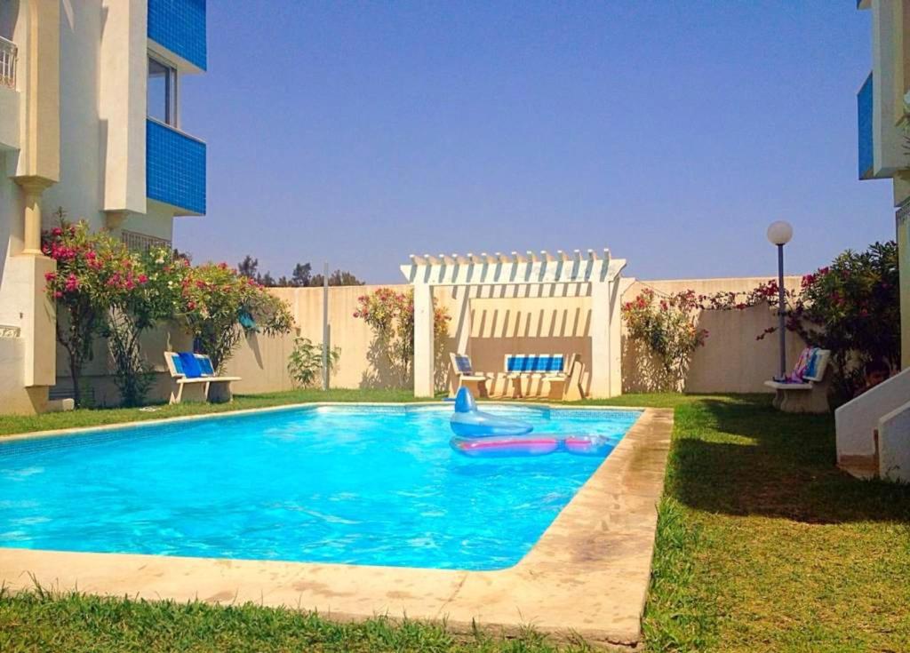 een zwembad in een tuin naast een gebouw bij 2 bedrooms apartement at Hammamet 100 m away from the beach with sea view shared pool and balcony in Hammamet