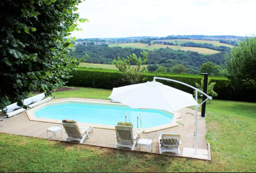 a swimming pool with chairs and an umbrella at Villa de 6 chambres avec piscine privee jardin clos et wifi a Mur de Barrez in Mur-de-Barrez
