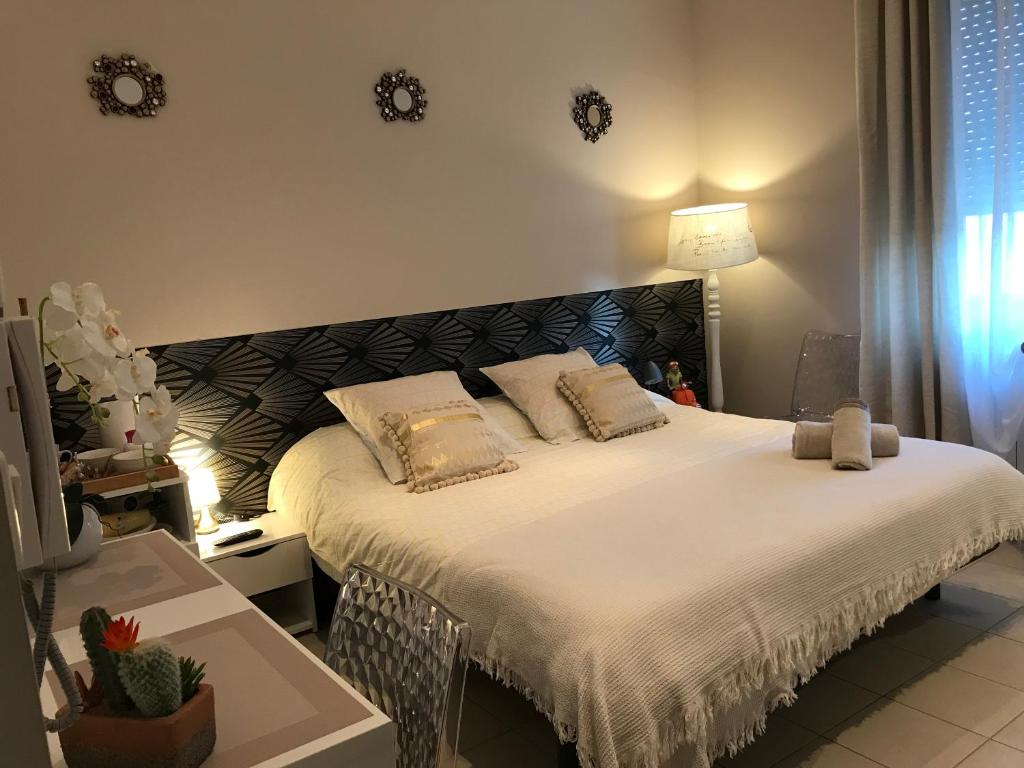 - une chambre dotée d'un grand lit avec des draps et des oreillers blancs dans l'établissement Le Marty, à Narbonne