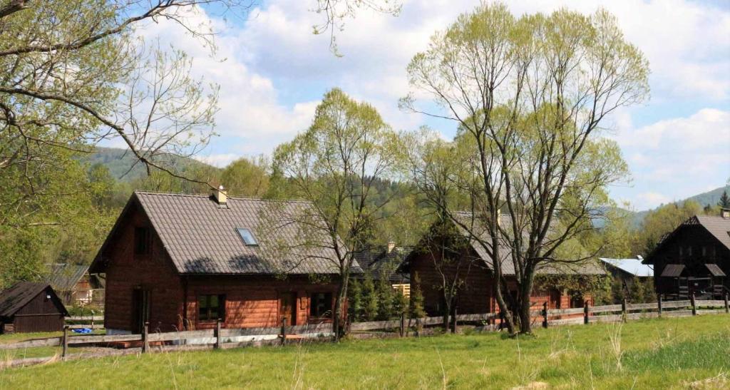 uma casa num campo com árvores e uma cerca em Chaty Rysia i Misia - całoroczne domy na wynajem em Wetlina