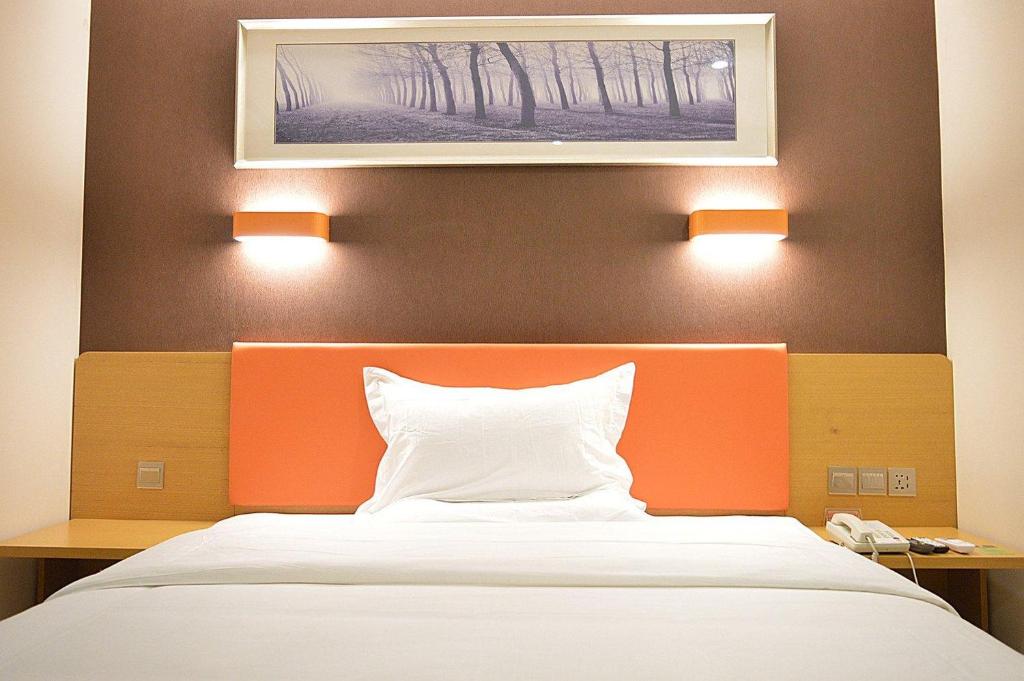 a bedroom with a bed and a painting on the wall at 7Days Premium Shijiazhuang East Railway Station Shenghe Square Branch in Shijiazhuang