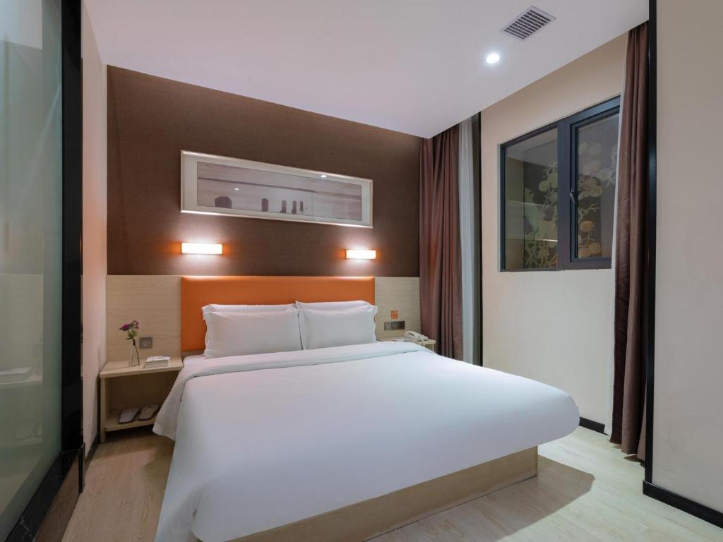 a bedroom with a large white bed and a window at 7Days Premium Shenzhen Airport T3 Terminal Branch in Shenzhen