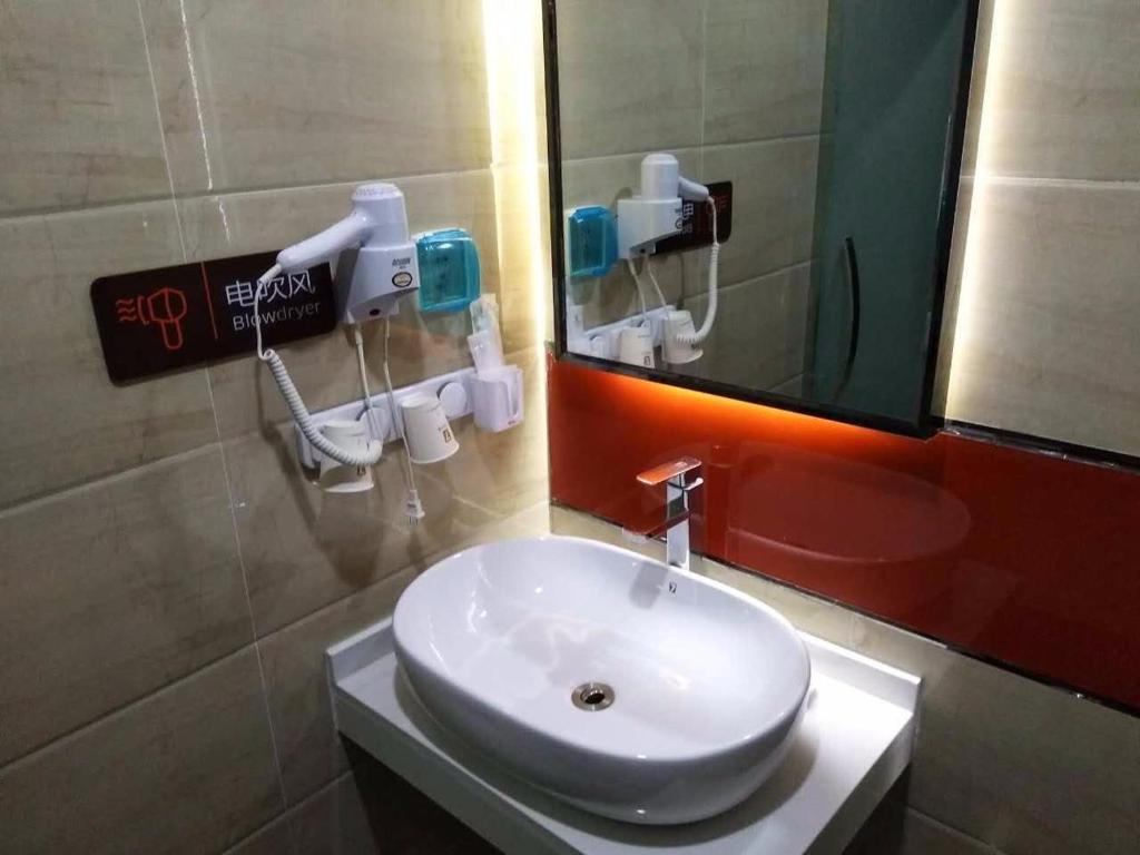 y baño con lavabo blanco y espejo. en 7Days Premium Kunming New Asia Sports City Subway Station Branch en Kunming