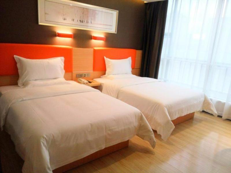 a hotel room with two beds and a window at 7Days Premium Chenzhou Guoqing South Road Branch in Chenzhou