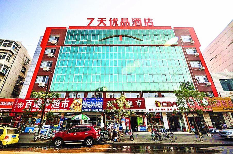 ein Gebäude in einer Stadt mit davor geparkt in der Unterkunft 7Days Premium Qinghuangdao Hebei Avenue Sidaoqiao Branch in Qinhuangdao