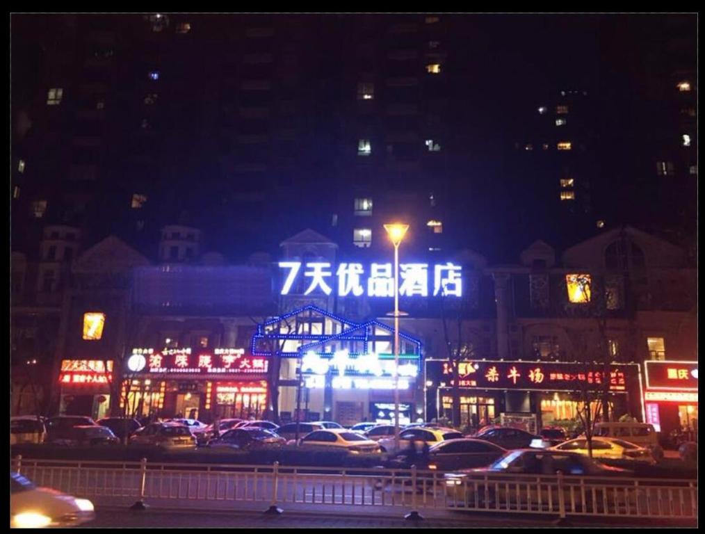 Una ciudad de noche con coches estacionados en un estacionamiento en 7Days Premium Yibin Riverside Branch, en Yibin