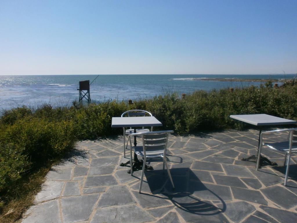 two tables and chairs sitting on a stone patio near the ocean at bord de mer in La Plaine-sur-Mer