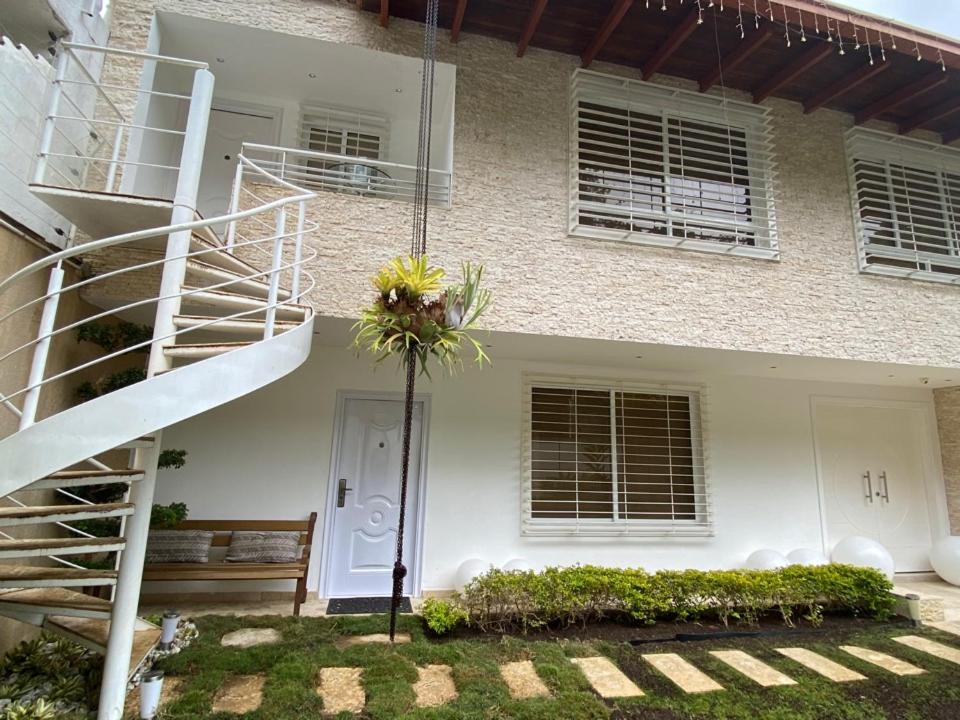 uma casa branca com uma escada em espiral em frente em Una casa con vistas en Caracas em Caracas