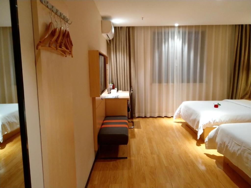 a hotel room with two beds and a desk with a mirror at 7Days Premium Chongqing Qijiang District Government Branch in Qijiang
