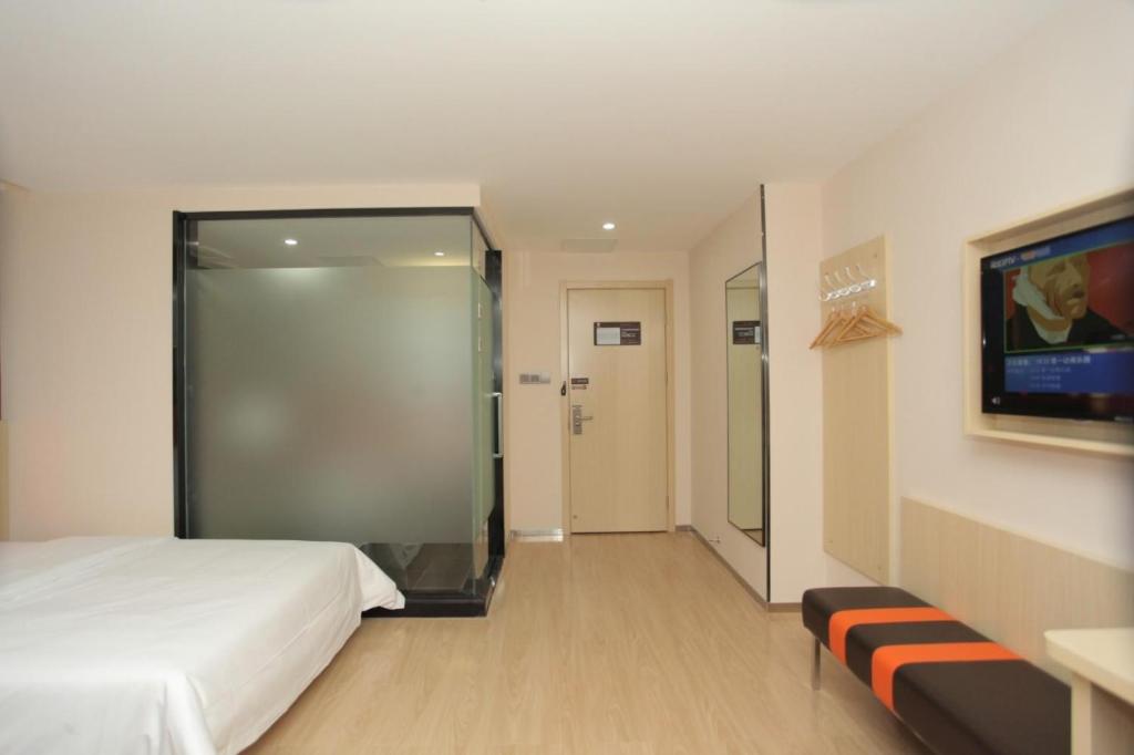 Habitación de hotel con cama y puerta corredera de cristal en 7Days Premium Baoding Qingyuan Jianshe North Road Branch, en Baoding