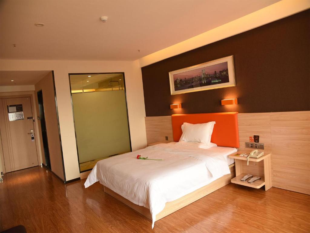 a bedroom with a large bed with an orange headboard at 7Days Premium Chongqing Baishiyi Hot Spring Capital Branch in Chongqing
