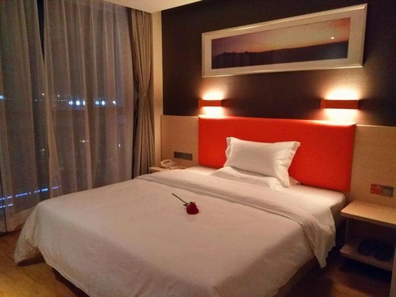 una camera da letto con un grande letto bianco con testiera rossa di 7Days Premium Chongqing Liangjiang New District Yufu Industrial Park Yuzui Branch a Chongqing