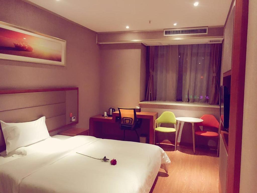 重慶市にある7Days Premium Chongqing Qibo Center Jintong Road Light-Railway Station Branchのベッド、テーブル、椅子が備わるホテルルームです。