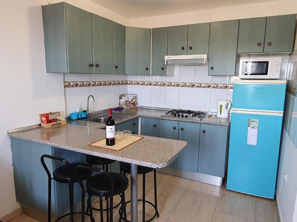 a kitchen with blue cabinets and a counter with a bottle of wine at Holla del Saldo in Ingenio