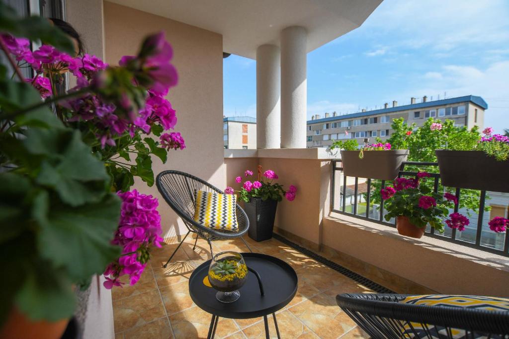 balcón con mesa, sillas y flores en Apartment Plaža, en Kladovo
