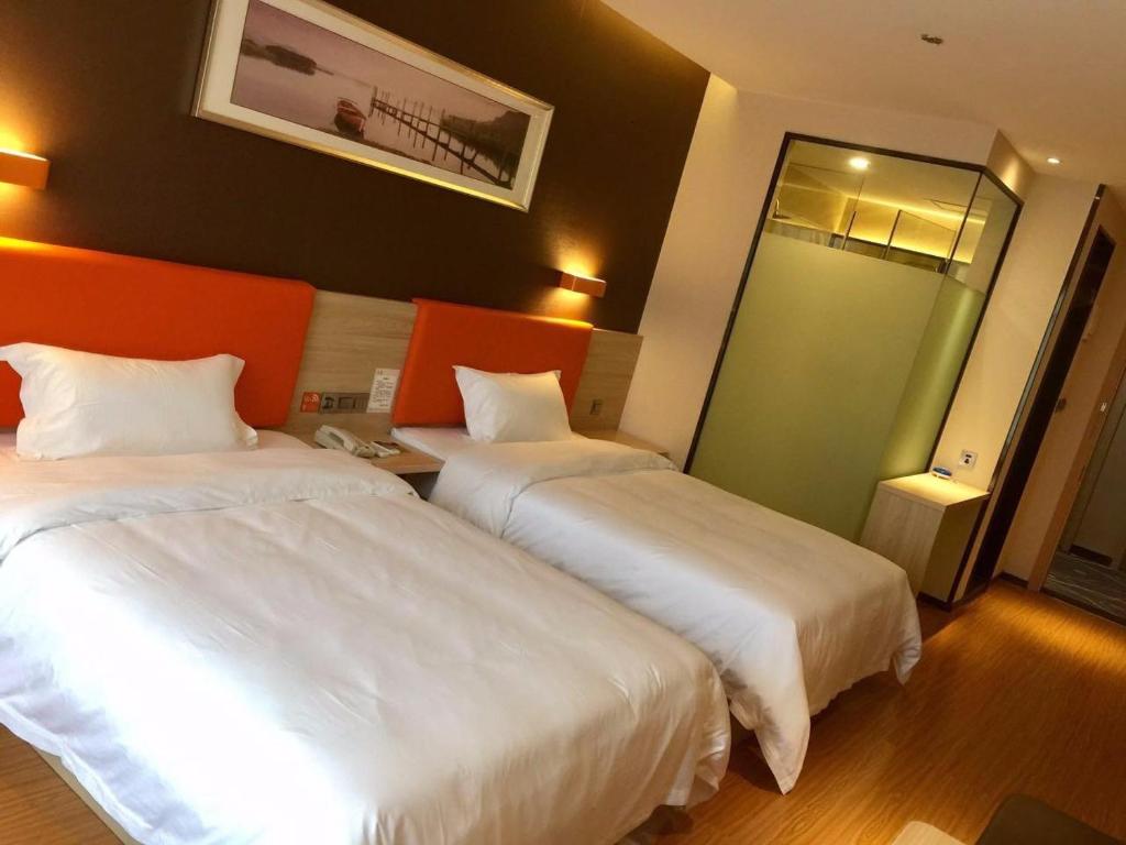 Dazuにある7Days Premium Chongqing Dazu Shike XIncheng Branchのベッド2台と鏡が備わるホテルルームです。