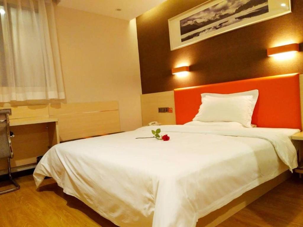 a bedroom with a white bed with a flower on it at 7Days Premium Guangzhou Zengcheng Xintang Plaza Branch in Guangzhou