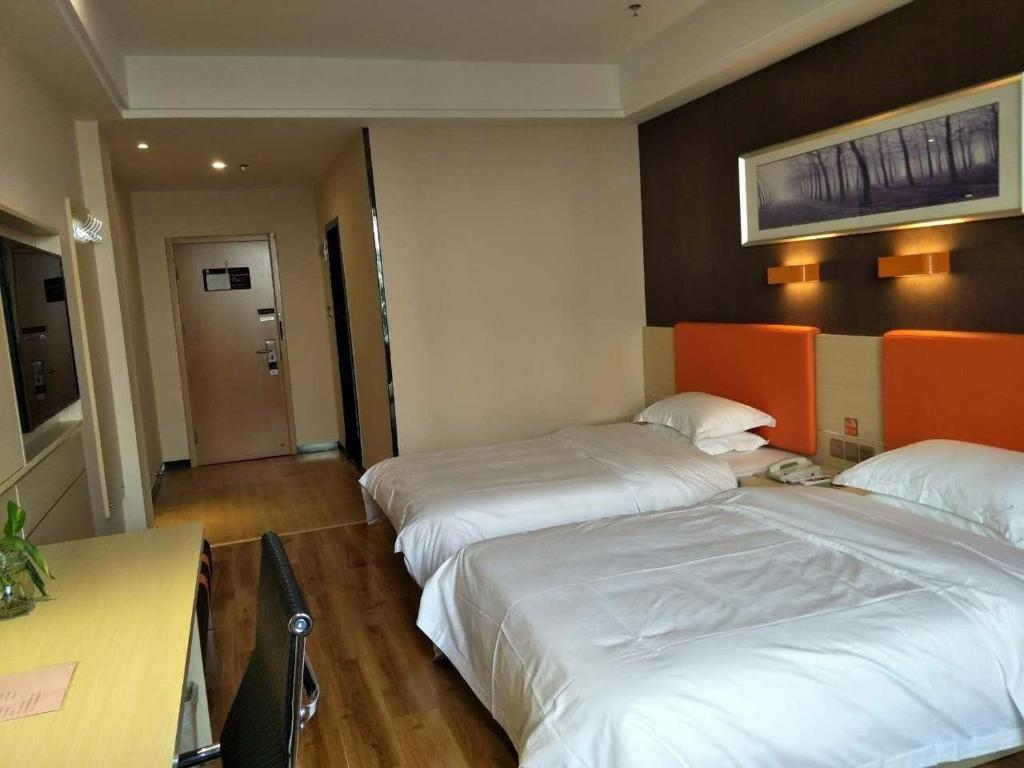 a hotel room with two beds and a desk at 7Days Premium Yi'ning Shanghaicheng Branch in Kipekyüzi