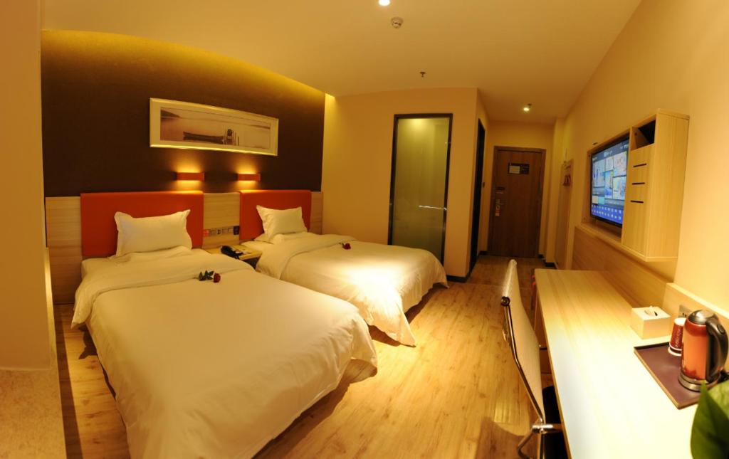a hotel room with two beds and a flat screen tv at 7Days Premium Yichang Wanda Plaza Canal Park Branch in Yichang