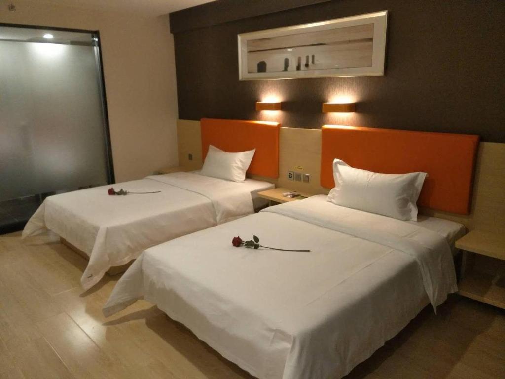 two beds in a hotel room with flowers on them at 7Days Premium Xingtai Railway Station Tianyi Street Branch in Xingtai