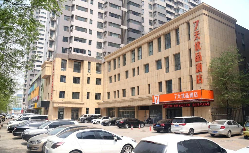 a parking lot with cars parked in front of a building at 7Days Premium Shijiazhuang Jianhua South Avenue South Second Ring Branch in Shijiazhuang